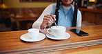 Hand, stirring and coffee cup on table in cafe, restaurant and bistro to enjoy hot beverage. Counter, expresso and cappuccino of woman or customer with tea, breakfast and caffeine in morning