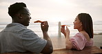 Couple, pizza and eating outdoor by beach for date, celebration and anniversary in California. Excited interracial man and woman with fast food or lunch on bench by sea or ocean for travel on holiday