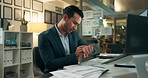 Busy, office and businessman checking watch with deadline, pressure and overtime with paperwork at computer. Late, night and frustrated man at desk with time management crisis, stress and overworked