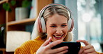 Happy woman, laughing and phone with headphones for streaming, watching movie or online subscription in living room at home. Female person with headset or mobile smartphone on sofa for entertainment