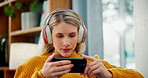 Woman, phone and watching with headphones for movie, online streaming or subscription in living room at home. Young female person in relax with headset or mobile smartphone on sofa for entertainment