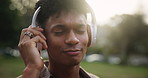 Black man, headphones and music in outdoor park, streaming song and online connection for sound. Male person, nature and listening to podcast in garden, relax and peace or calm audio for wellness
