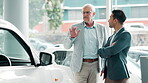 Car dealership, negotiation or retail with customer and salesman on showroom floor for choice or option. Advice, consulting and decision making with trader talking to mature client for vehicle deal