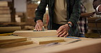 Man, hands and carpenter with sand paper for smooth, soft or refined finished at workshop. Closeup of male person, artisan or woodworker dusting block, timber or lumber on workbench at warehouse