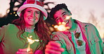 Couple, outdoor and face with fun spark for celebration, festival and party at sunset together. Happy, smile portrait and night event with firework, light and glow at park with love, bonding and care