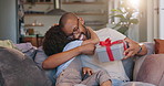 Happy dad, child and hug with gift on sofa for fathers day surprise, love or gratitude at home. Papa with smile for ribbon present or box on living room couch with son, little boy or kid at house