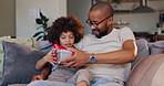 Happy dad, child and box with gift on sofa for fathers day surprise, love or gratitude at home. Papa with smile for ribbon present or parcel on living room couch with son, little boy or kid at house