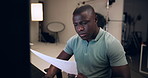 Black man, photographer and reading with documents for production, budget or expenses at studio. Young African, male person or producer checking paperwork for bills, finance or script at workplace