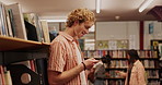 Bookshelf, happy and man with phone in library for social media, update and education network. Person, laughing and student with technology at academy for campus gossip, online post and notification