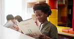 Smiling, black boy and book in classroom for educational development, mind growth and language learning. Student, reading or studying in school library for creative knowledge and storytelling