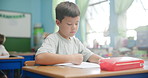 Classroom, drawing and boy with book, education and school with learning, creativity and artistic. Child development, kid and student with ideas, relax and writing with studying, paper and knowledge