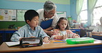 Education, teacher and kids in classroom for help, explain and learning in elementary school. Woman, students and diversity at desk for solution, assessment and knowledge while coloring together