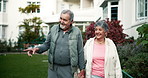 Couple, holding hands and walk in garden for retirement, discussion and point at plants in morning. Elderly woman, old man and happy with care, bonding and love on path in nature at nursing home