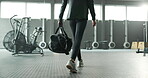 Woman, legs and walking with bag in gym, wellness and health club with athlete for workout challenge. Exercise, determination and body development, routine and shoes for confident commitment