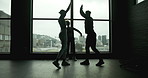 Celebration, high five and friends in gym with happiness collaboration for workout goals. Success, motivation and group silhouette of athletes cheer by window for fitness achievement in sports center