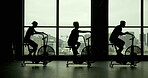 People, bicycle machine and fitness in gym for exercise, commitment and silhouette in sports club. Spin class, group and cycling on equipment with motivation, cardio and endurance or weight loss