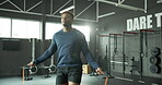 Man, skipping rope and fitness in gym, jumping exercise and cardio workout for strong leg muscles. Training, energy and wellness routine, equipment and activity in health club, movement and challenge