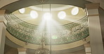 Islamic, mosque and interior of building ceiling with sunlight, chandelier and arabic writing for religious worship. Architecture, muslim temple and prayer room with mosaic design or Urdu scripture