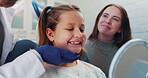 Healthcare, dentist and child with mirror for checkup, oral examination and consultation. Hospital, mom and little girl with female orthodontist for teeth surgery, trust and discussion in clinic