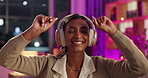 Music, headphones and Indian girl with sofa dance celebration in house with weekend, relief and good mood. Happy, radio and gen z person streaming audio in neon apartment with night, chill or listen