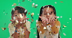 Happy children, blowing and celebration with confetti on green screen, studio or background. Portrait of excited little boy and girl with smile, glitter or sparkles for festive, party or new year