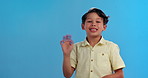 Smile, wave and boy child in studio with hello, positive attitude and happy face on mockup space. Portrait, greeting and kid on blue background for introduction, pride and cool confidence for welcome