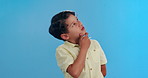 Boy, child and thinking in studio with ideas, mockup space and questions for learning, growth and development. Doubt, decision and curious kid on blue background with inspiration, insight and choice