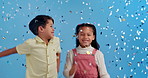 Fun, friends and children in studio with confetti for kids party, happy winning or prize giveaway. Congratulations, excited boy and girl dancing in celebration with glitter, smile and blue background