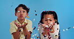 Blow, friends and children in studio with confetti for kids party, happy winning or prize giveaway. Congratulations, excited boy and girl in fun celebration with glitter, smile and blue background