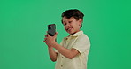 Boy, child and selfie in studio with smile, memory and mobile app for memory by green background. Kid, happy and photography, excited and recording video with trendy shirt, playful and development