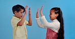 High five, happy and face of children in studio for friendship, support and collaboration. Youth, childhood and portrait of girl and boy with gesture for love, fun and celebrate on blue background