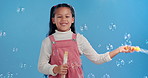 Fun, blow and girl in studio with bubbles for magic, playing and games for growth, development or celebration. Child, soap and liquid solution for playful entertainment, curiosity and blue background