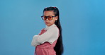 Attitude, sunglasses and face of child on blue background for confidence, trendy style and cool accessories. crossed arms, youth and portrait of girl with eyewear for joy, pride and cute in studio