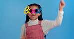 Dance, sunglasses and face of child in studio for confidence, trendy style and cool accessories. Happy, excited and portrait of young girl with eyewear for fashion, pride and cute on blue background