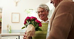 Senior, couple and happy for flowers in kitchen with surprise for celebration of anniversary, relationship and romance. Old man, woman and together in home with kiss for affection, bonding and love.