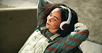 Happy girl, relax and sofa with headphones for music, playlist or audio on holiday at home. Young female person lying on couch or enjoying songs, album or podcast with headset in living room at house