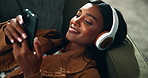 Happy woman, relax and sofa with headphones for music, playlist or audio on holiday at home. Young female person lying on couch or enjoying song, album or podcast with tech in living room at house