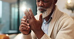 Joint pain, care and hands of senior black man at home with arthritis, physio therapy or massage for relief. Elderly male person, wrist injury or osteoporosis in lounge with treatment for muscle ache