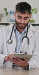 Doctor, man and typing on tablet in hospital for healthcare research, review and history report of diagnosis treatment. Medic, digital and Telehealth of schedule, information and insurance medicine