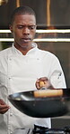 Black man, chef and cooking food in kitchen with pan on fire, speed and flavour development of cuisine technique. Person, culinary and flame for frying, safety toss and traditional meal at restaurant