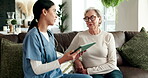 Senior, woman and nurse in house with tablet, healthcare and consultation for diagnosis in nursing home. Lounge, professional and medical caregiver or talking, patient and telehealth app for results