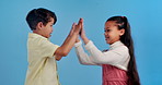 High five, happy and face of kids in studio for friendship, support and collaboration. Youth, childhood and portrait of girl and boy with gesture for love, fun and celebrate on blue background