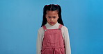 Girl, upset and angry face in studio on blue background for moody, tantrum and annoyed attitude. Grumpy, frustrated and portrait with furious or disagreement on backdrop for cross, fight and problem