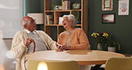 Senior couple, conversation and laughing in house with love in retirement for marriage, happiness and funny. Elderly people, joke and smile by table in lounge with care, support and trust for bonding