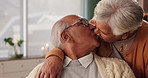 Elderly couple, relax and kissing in house with love in retirement for marriage, happiness and funny. Senior people, hug and smile on sofa in living room with care, support and trust for bonding