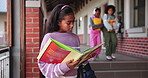 Child, girl and reading book in school for learning, education and development as student in outdoor. Female learner, knowledge and pride for growth, skills and scholarship in literacy or numeracy
