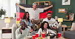 People, German flag and celebration on sofa watching tv for soccer, world cup or sport event in living room. Clapping, diversity and friends with alcohol, happiness or goal from football team in home