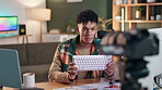 Camera, influencer and promotion for product, keyboard and man in living room with mic for advertising. Home, feedback and content creation for blogger for gaming equipment, online and lounge