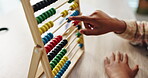 Counting, child and hand on desk, abacus beads and closeup of education and student in middle school. Classroom, studying and practice for exam of maths, growth and development of kid on table