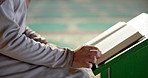 Muslim person, hands and podium with quran at mosque for god worship, knowledge or words of Allah. Closeup of islamic scripture, religious or holy book for information or arabic literature at temple